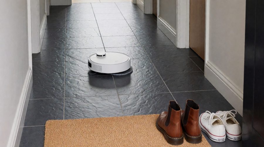 Robot vacuum and mop cleaning a tiled hallway floor